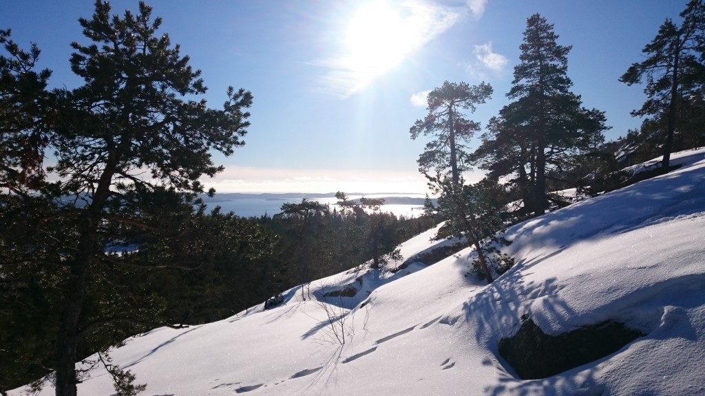 Snöig backe i 45 graders lutning med solen högt på en blå himmel.